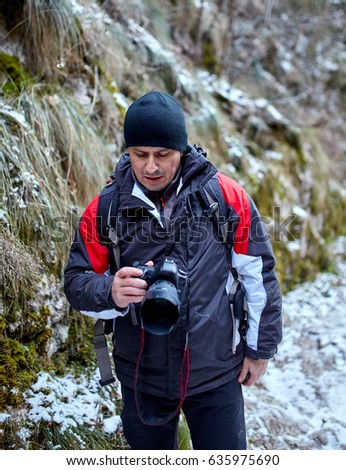 Man photographer hiking on mountains in wintertime