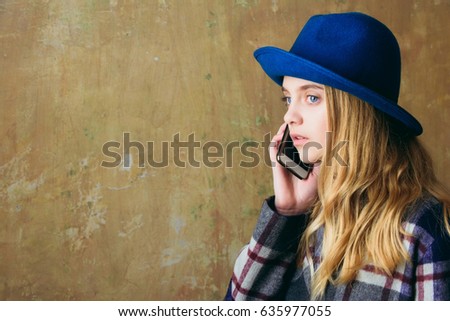 caucasian girl speak or talking on phone, woman hold smartphone in green hat on beige background, copy space