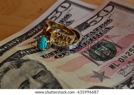 Silver and gold wedding rings on top of two fifty dollar bills