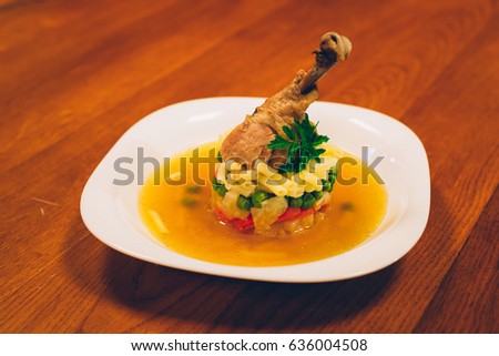 chicken soup ÚJHÁZY with chicken leg and vegetables, wooden table