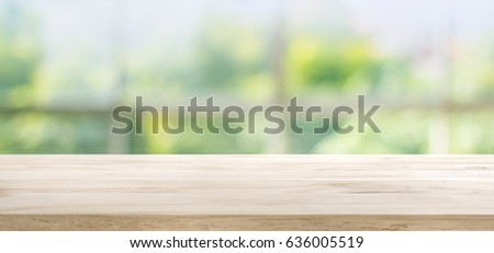 Wood table top on blur of window glass and abstract green from garden with city view in the morning background.For montage product display or design key visual layout background.