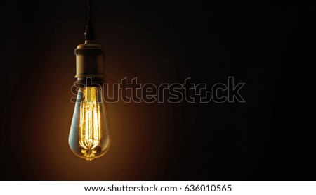 Vintage hanging Edison light bulb over dark background Royalty-Free Stock Photo #636010565
