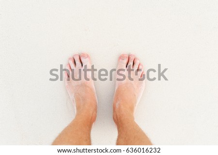 Man's legs on the white sand Indian ocean