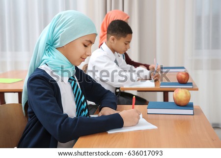 Cute girl sitting at desk in school class