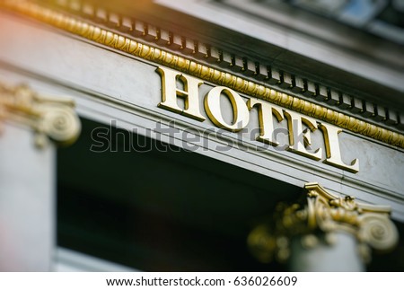 Sun flare above hotel word with golden letters on luxury hotel with beautiful columns