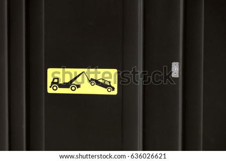Yelow sign on black garage door - traffic sign - no parking, tow away zone sign