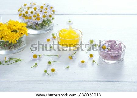 cosmetic product samples with herbal flowers on white wooden table 