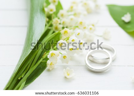 white flowers and wedding rings on bright wood table