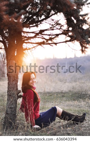Beautiful smiling lady sitting under a tree with sunset on background