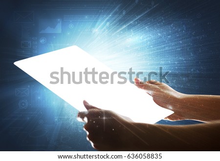 Young female hand holding a tablet with faded charts in the background