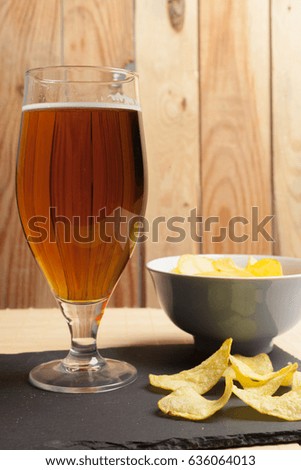 Lager beer in glass and potato chips on wooden background
