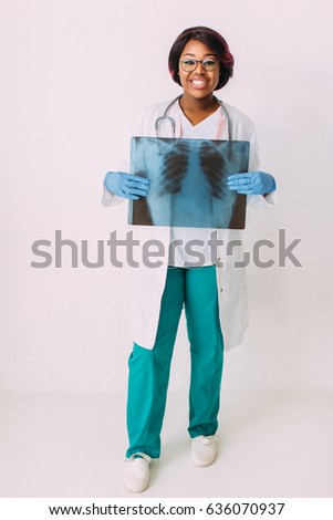 Young African American doctor in medical mask looking at x-ray image