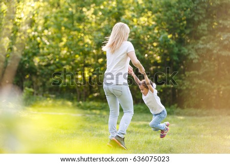 Mother and daughter playing circling around at the park on beautiful. Mother turns little daughter in circle