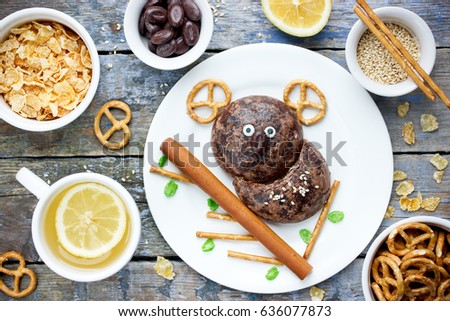 Food art for kids - funny koala on the tree from gingerbread, straw, pretzels, candy and cereal. Edible picture on a plate composition