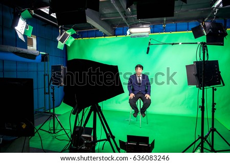 Behind the scenes of TV movie video film shooting production crew team and camera lighting set in the big studio , A television presenter in a TV studio with a camera and lighting equipment