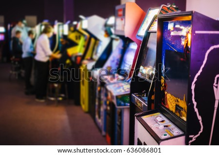 Old Vintage Arcade Games in a dark room and players playing video games in the background Royalty-Free Stock Photo #636086801
