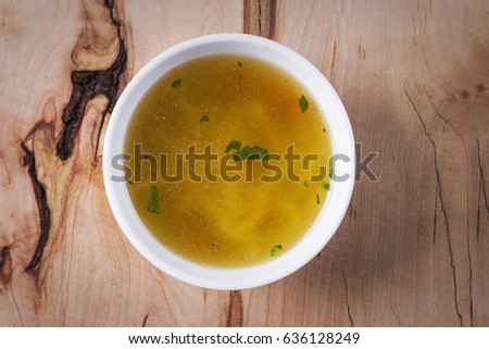 Chicken soup on a rustic wooden table, top view