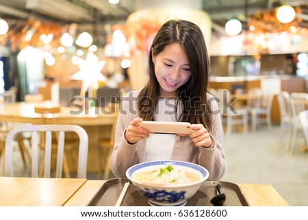 Woman taking photo on her noodles in restaurant