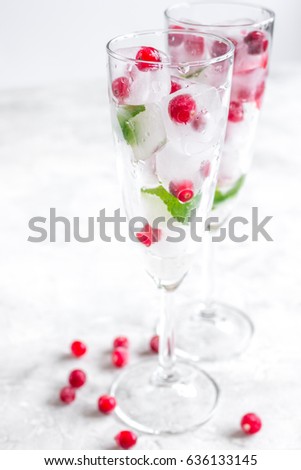 Ice cubes with berries and mint in glasses for summer drink white background
