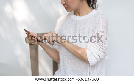 Half length of young happy beautiful woman using her mobile phone on white wall background.