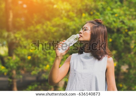 young beautiful dark brown haired woman drinking water at summer green park Royalty-Free Stock Photo #636140873