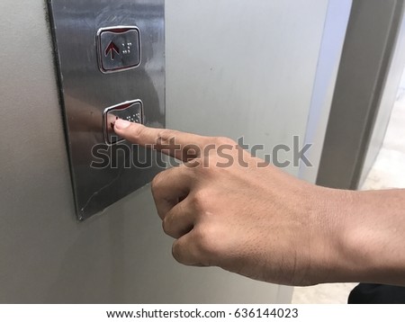 Businessman hand touching going down sign on lift control panel
