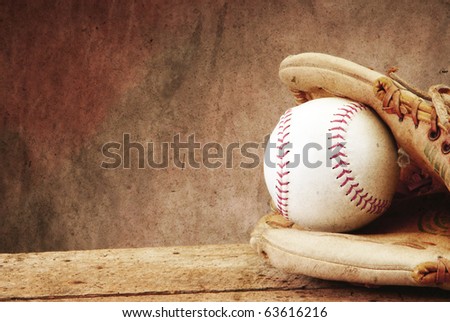 Textured for antique look Baseball/softball with mit on old wood table and tan aged background with copy space