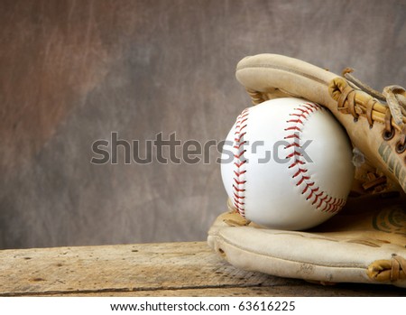 Baseball/softball with mit on old wood table and tan aged background with copy space