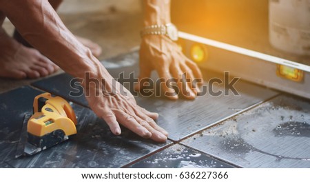ceramic tiles. the worker's hand tile in position over adhesive with lash tile leveling system.selective focus.vintage tone Royalty-Free Stock Photo #636227366