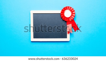 photo of cute prize ribbon and empty blackboard on the wonderful blue studio background 