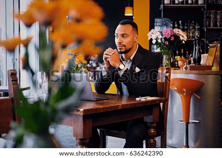 Portrait of elegant black male using a laptop in a restaurant.