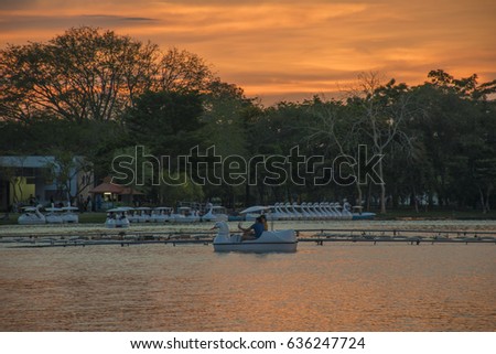 happy couple take selfi on duck boat in lagoon at public park at sunset