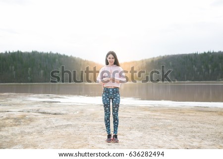 Young woman peaceful meditating by the lake. Fitness girl doing yoga at morning sunrise in nature background
