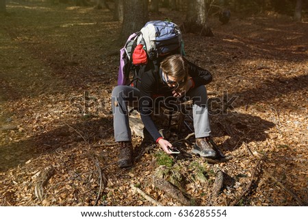 Hiker taking photographs on her hike through the woods. Memory collection, active lifestyle, mobile phone dependency concept. 
