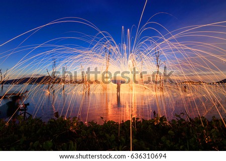 Burning steel wool spinning on lake. Amazing fire steel wool. Hot Golden Sparks Flying from Man Spinning Burning Steel Wool into the Lake at Pattaya, Thailand. Long Exposure 