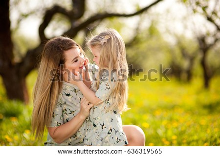 A little girl with her mother on a walk in the spring garden, socialize, laugh, embrace, rejoice, mother and daughter