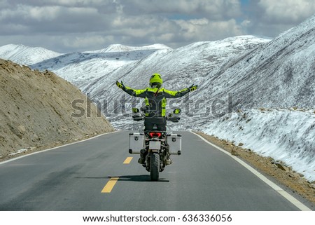 Men standing on motorbike while driving and free hands in snow moutain,Sichuan,China Royalty-Free Stock Photo #636336056