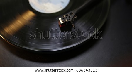 Low key photo of Turntable arm and cartridge playing on the spinning vintage vinyl record,iconic of the aesthetic of rock,blues,jazz,folk music,the trendy slow life style with selective focus.