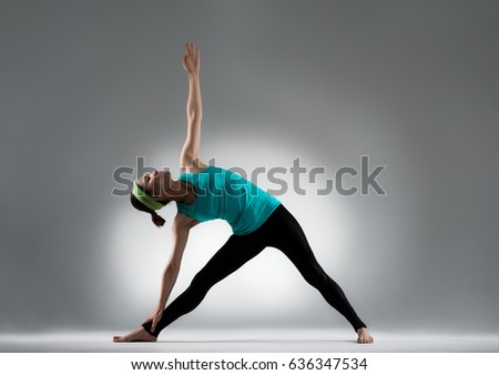 beautiful yoga player hold an ankle stretch body and hand extends to top enjoy meditation fitness posture in gray wall background studio.