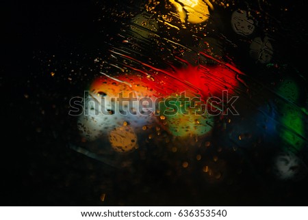 Rain drops on a windshield with blurry colorful lights