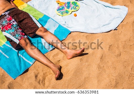 low section of a man relaxing on a colorful beach towel Royalty-Free Stock Photo #636353981