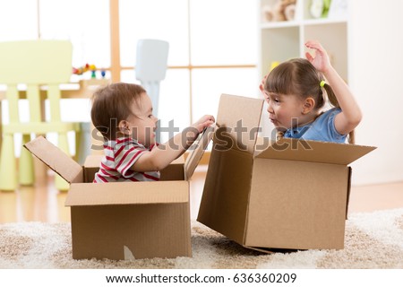 Kids girl and boy in their new home having fun with cardboard boxes.