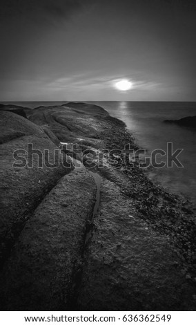 Seascape rock on the beach with sunset in black and white