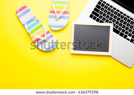 photo of empty blackboard, colorful sandals and cool laptop on the wonderful yellow studio background