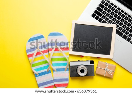 photo of empty blackboard, colorful sandals, retro camera, cute gift and cool laptop on the wonderful yellow studio background