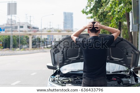 asian man stand in front of a broken car needs assistance looking under opened hood, a difficult situation Royalty-Free Stock Photo #636433796