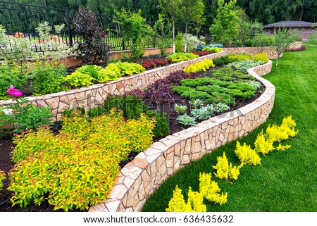 Landscape design of nice home garden, natural landscaping with decorative stones in residential house backyard. Luxury flowerbed and beautiful plants in summer, green upscale landscaped back yard. Royalty-Free Stock Photo #636435632