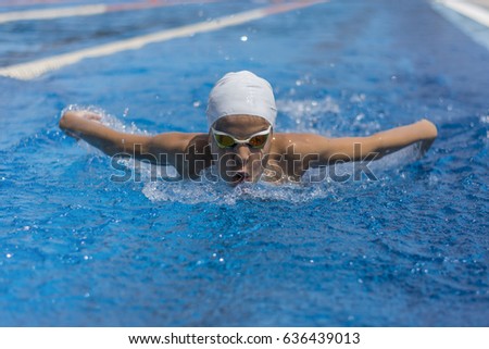 Close up action shot of child athlete swimming butterfly stroke Royalty-Free Stock Photo #636439013