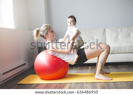 A sports mother is engaged in fitness and yoga with a baby at home