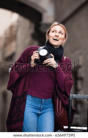 Happy positive girl taking picture with camera in the town